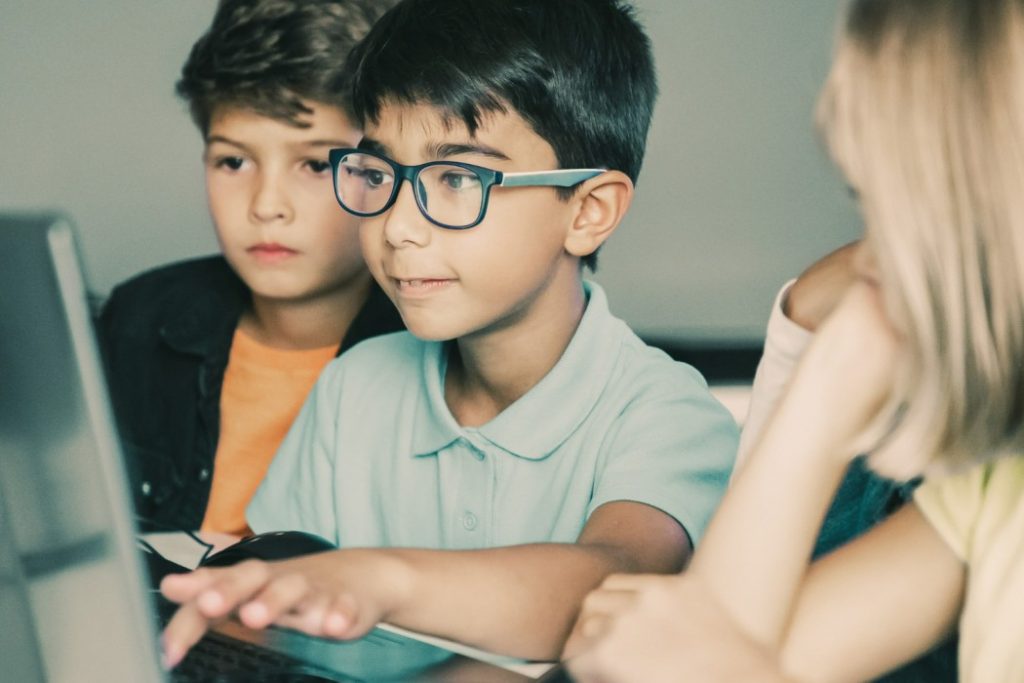 asian boy typing laptop keyboard classmates sitting table watching him doing task together 1