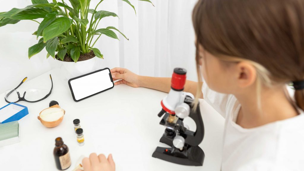 high angle girl looking into microscope holding smartphone 1